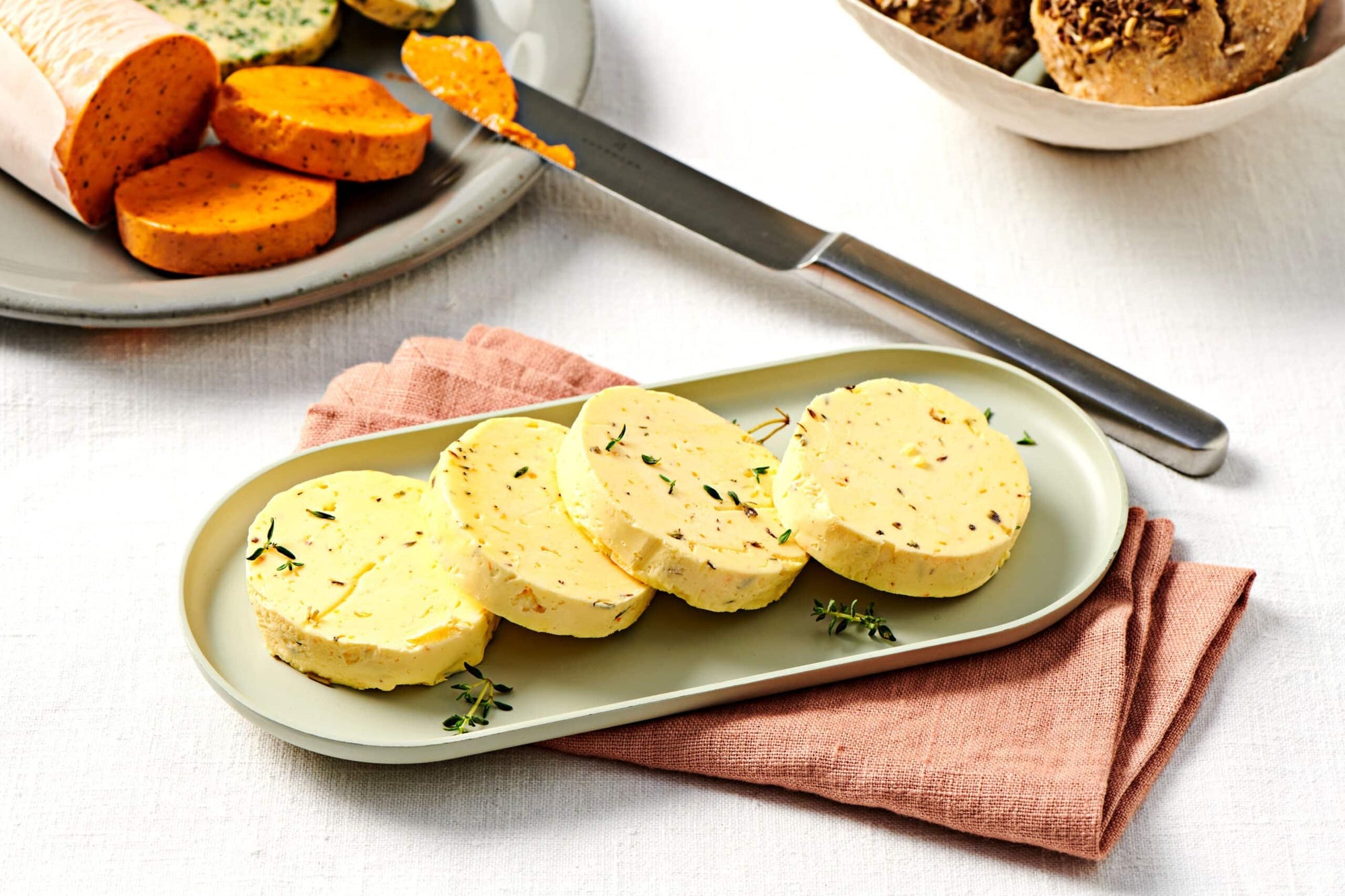Boudin de beurre aromatisé à l'orange et à la lavande parfumé au thym Fuchs, présenté en rondelles sur planche