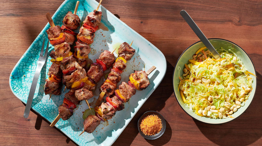 Brochettes de porc marinées à la bière grillées au barbecue avec salade de crudités carottes chou mangue cacahuètes assaisonnée gingembre