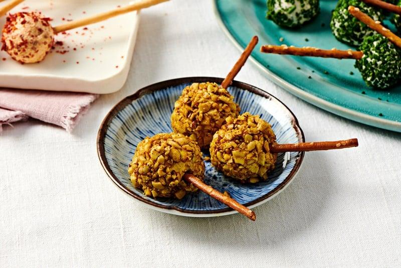 Sucettes apéritives de boulettes de fromage frais au curry gold enrobées d'éclats de noix de cajou et curcuma Fuchs avec un gressin fin